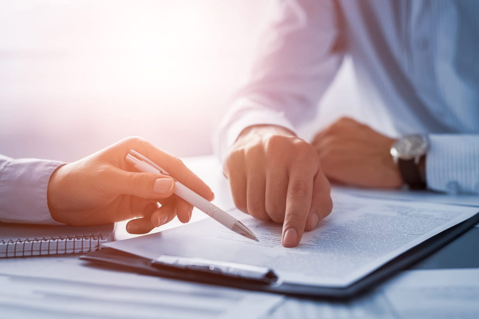 Close-up view of two attorneys’ hands pointing at a document on a clipboard.