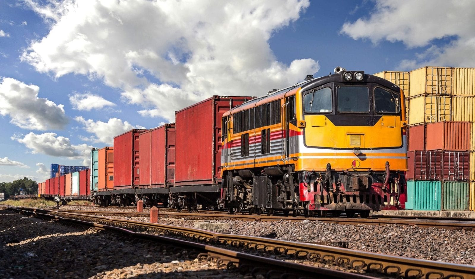 A freight train passes a shipping yard while traveling on a railroad.