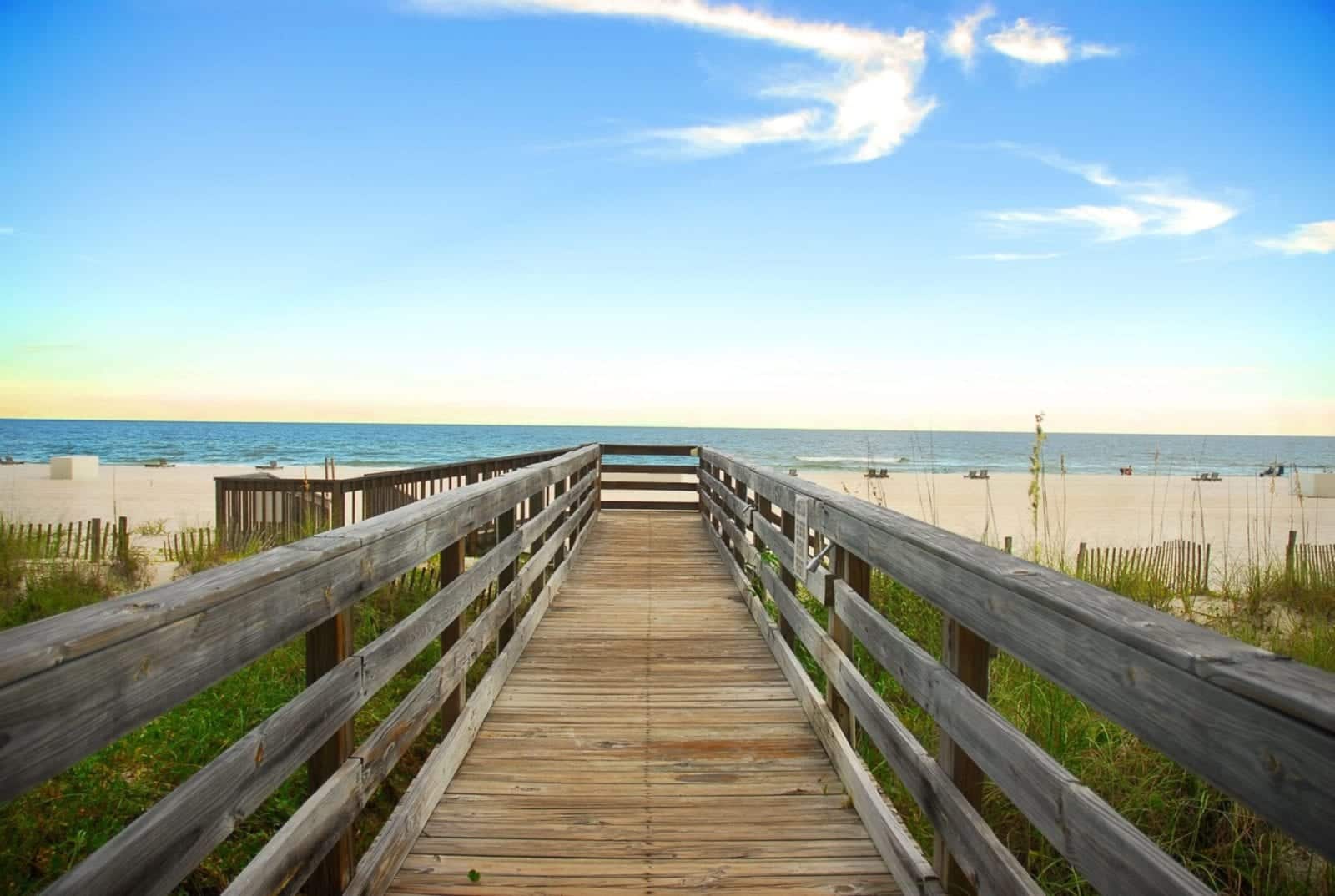 A walkway with stairs leading down to the beach on a sunny day.