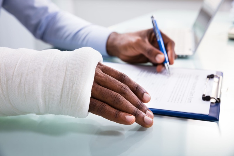A person with their arm in a cast reviews and signs their medical bill.