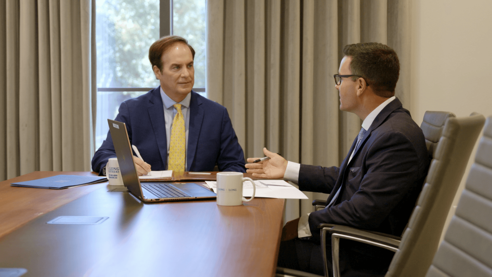 Attorneys Earle Long and Trip Smalley sit at a conference table discussing a car accident case in their Mobile, Alabama office.