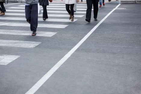 Close-up of pedestrians crossing a street at a marked crosswalk.