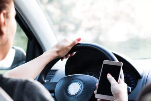 A woman uses her cell phone while driving.